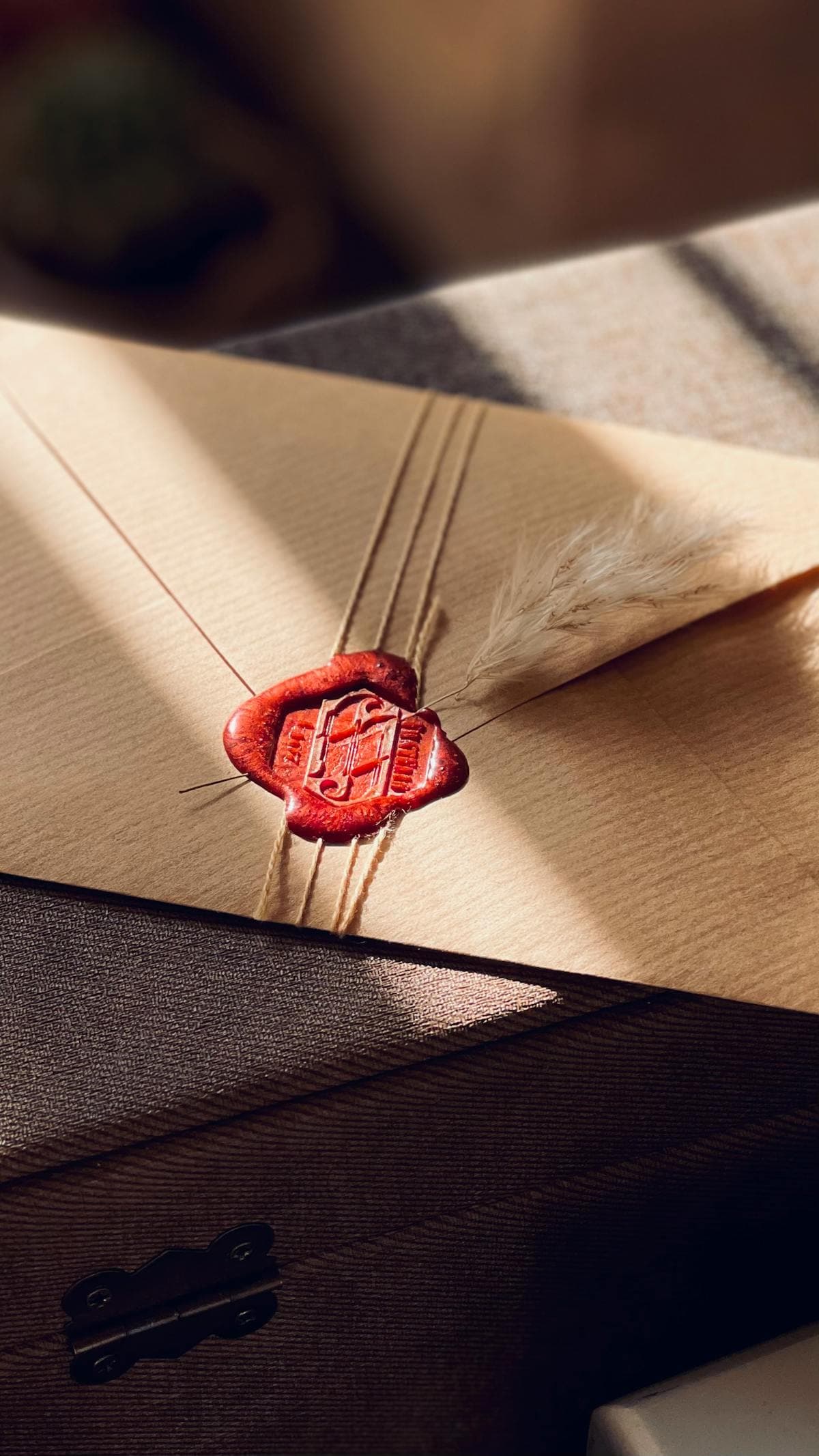 A sealed envelope with a crimson wax seal, bathed in warm golden light